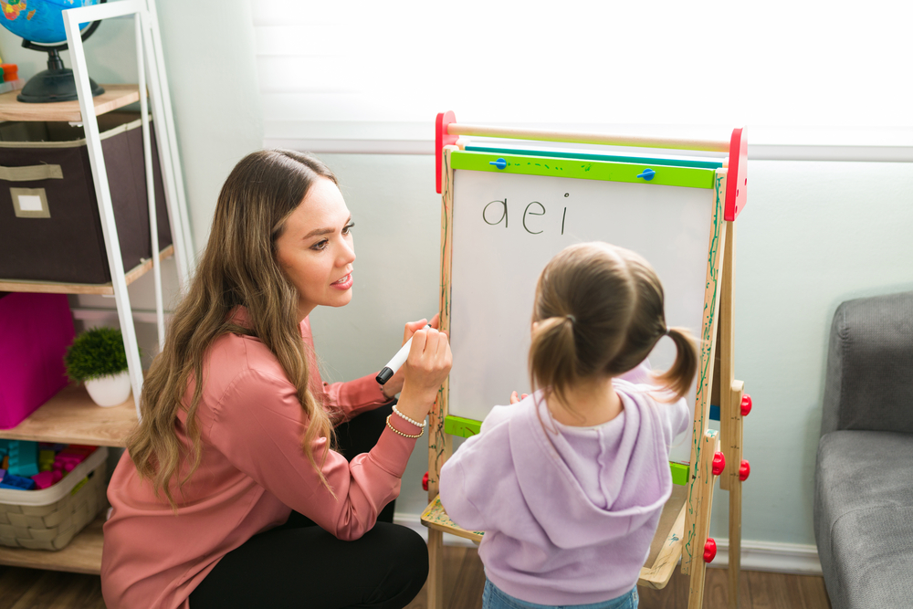 Teacher teaching vowels to kid in classroom