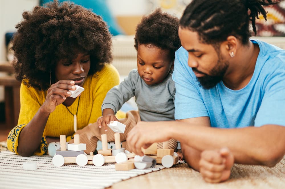 Parents and child playing with colors and shapes toys on the floor